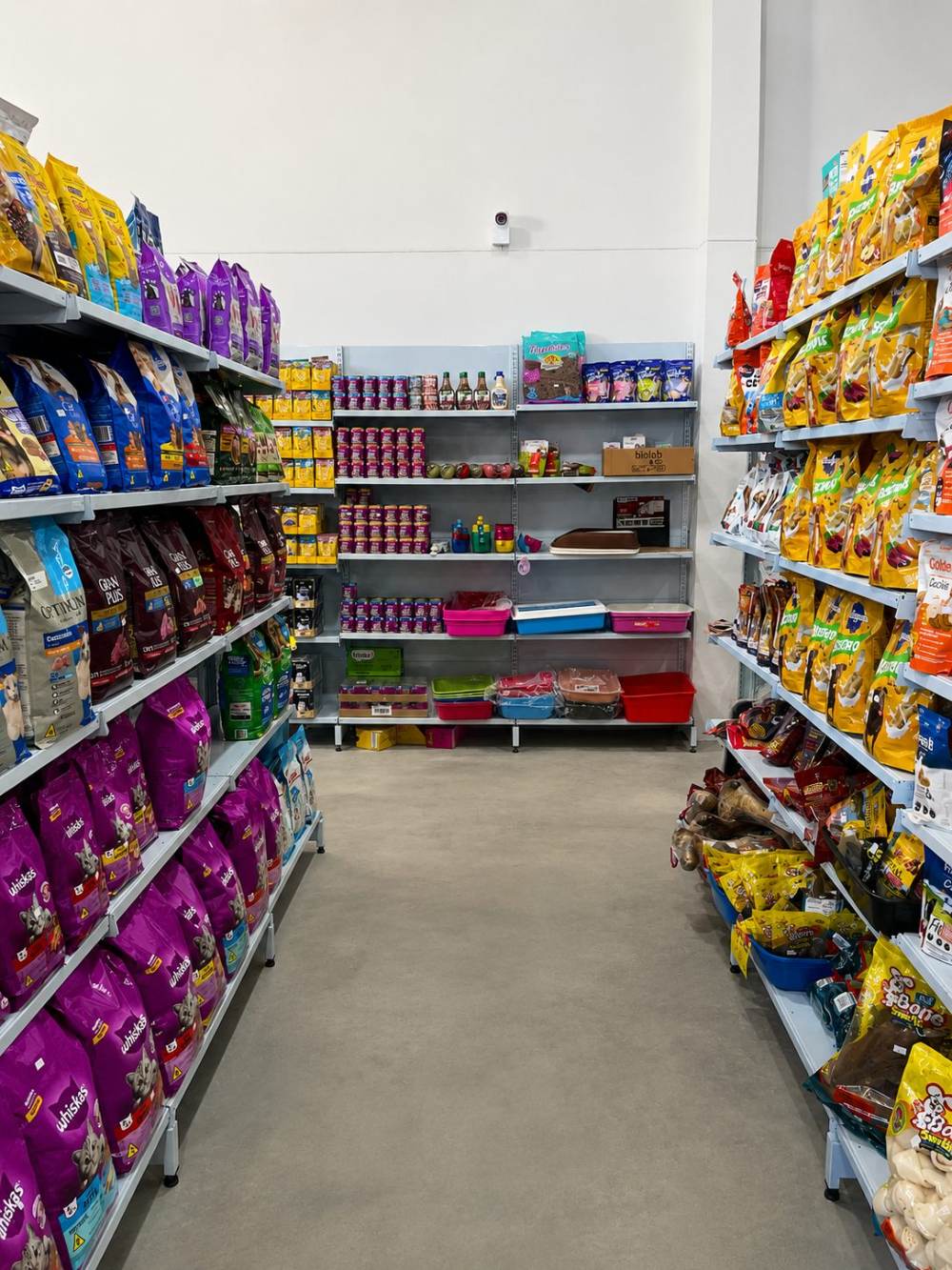 Corredor com rações para gatos, petiscos, caixas sanitárias e potes.